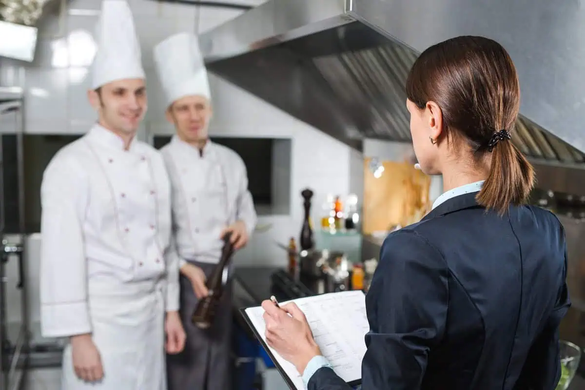 Female contractor discussing kitchen plans with restaurant chefs in white uniforms