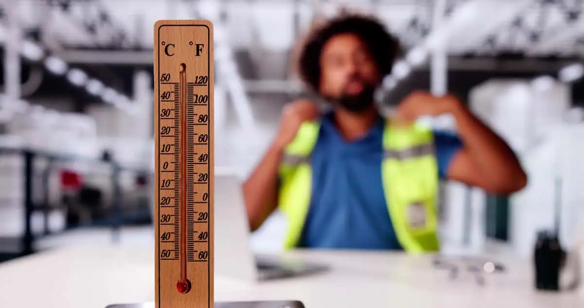Close-up of a thermometer with a construction worker blurred in the background