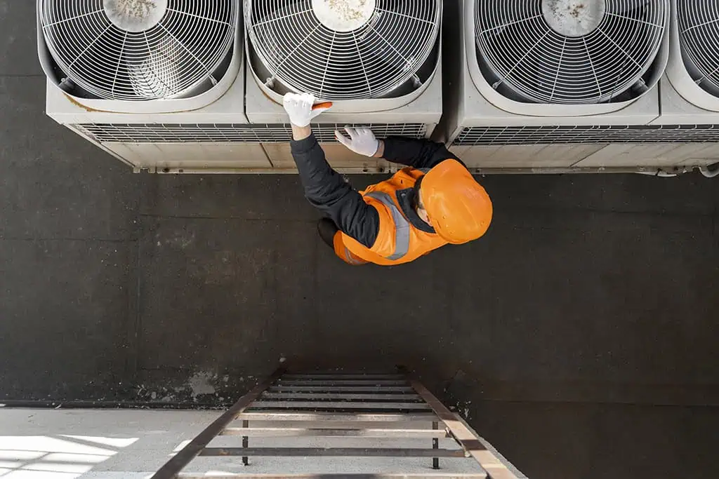 Construction worker servicing rooftop HVAC split unit on a restaurant building