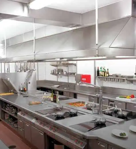 Commercial restaurant kitchen with stainless steel exhaust hoods over cooking stations